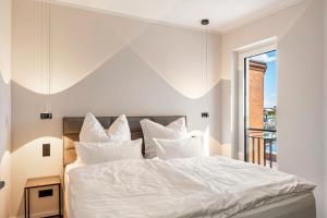 ヴィッテンベルゲにあるElbe6 - 5 Sterne Apartmentsの白いシーツと窓のあるベッドのある寝室