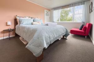 une chambre avec un grand lit et une chaise rouge dans l'établissement Isobel's Rose Cottage, à Hanmer Springs