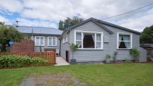 une maison blanche avec une clôture dans une cour dans l'établissement Isobel's Rose Cottage, à Hanmer Springs
