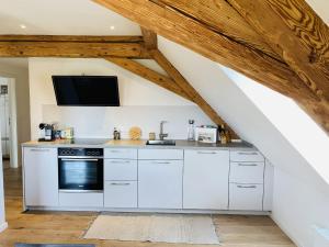a kitchen with white cabinets and a tv on the wall at Ferienwohnung Haus Alpenblick in Lenzkirch