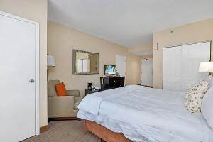 a bedroom with a large white bed and a couch at Stylish King Apt w Arcade Game & BBQ Near Disney in Orlando