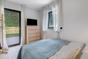 a bedroom with a bed and a tv and windows at Stackler54 - mit Garten in Neustift im Stubaital