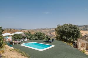 une piscine avec chaises et parasols dans une cour dans l'établissement Finca El Porvenir, à El Gastor