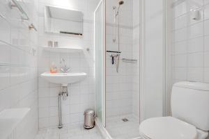 a white bathroom with a toilet and a sink at Ferienhaus Petten aan Zee in Petten +17 photos