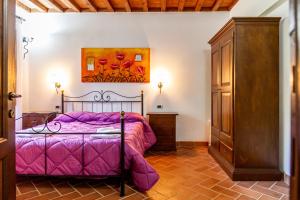 マッサ・マリッティマにあるCasa Vacanza Il Carpignone 7のベッドルーム1室(紫色のベッド1台付)が備わります。壁に絵画が飾られています。 +22枚の写真