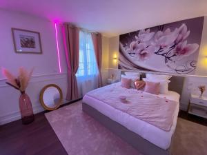 a bedroom with a large bed with pink lighting at Le Cocon Diamant Jacuzzi & Sauna in Compiègne
