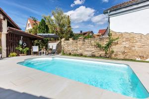 a swimming pool in a backyard with a stone wall at Ferienwohnung Pinot Noire in Müllheim