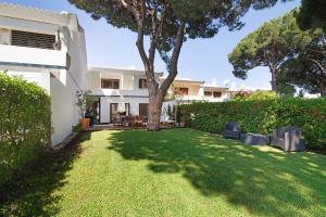 a yard with chairs and a tree in front of a house at Vilamoura com Piscina e Wifi in Vilamoura