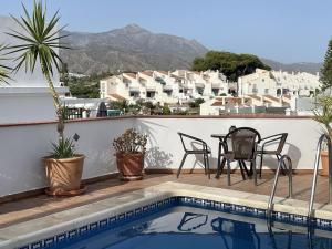a balcony with a table and chairs next to a swimming pool at Salida Del Sol in Nerja