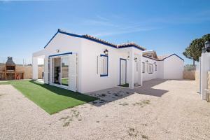 ein weißes Haus mit grünem Rasen davor in der Unterkunft Villa Flora in Algoz