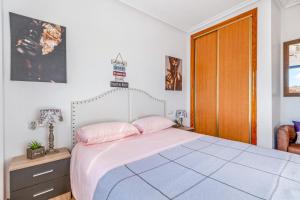 a bedroom with a bed with pink pillows at Apartamento Mandarín Playamarina 2 in Orihuela