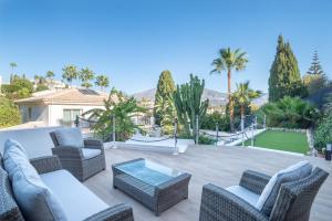 ミハス・コスタにあるVilla Jazminの籐家具とガラステーブル付きのパティオ