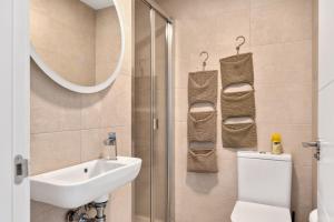 Un baño con lavabo, inodoro y espejo. en Real de Ifach - Atico, en Empedrola 18 fotos más