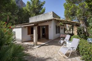 uma pequena casa branca com duas cadeiras em frente em Vacanze e Relax Frassino em Custonaci