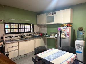 Una cocina con gabinetes blancos y una mesa y un refrigerador. en La morena, en Ezeiza