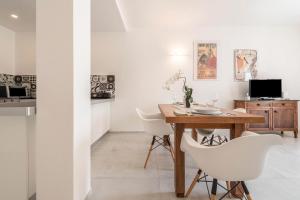 a kitchen and dining room with a wooden table and white chairs at Comfort Appartamento Le Cementine in Tremosine Sul Garda
