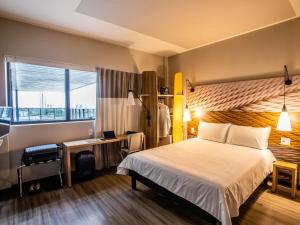 a hotel room with a bed and a desk and a window at ibis Palmas Avenida JK in Palmas