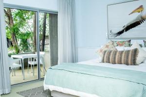 een slaapkamer met een bed en een balkon met een tafel bij The Village Suites in Windhoek
