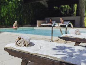 フィジャックにあるMercure Figeac Viguier du Royの2つのベッドとプールにいる人々がいるプール