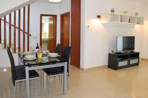 een eetkamer met een tafel, stoelen en een televisie bij Villa Mariesa in Playa Blanca