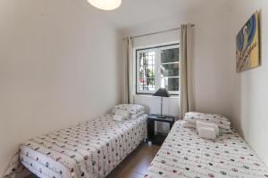 zwei Betten in einem kleinen Zimmer mit Fenster in der Unterkunft Old Village Vilamoura in Quarteira