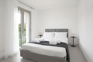 a white bedroom with a large bed with white sheets and pillows at Baseventuno 4 Bilocale in San Martino della Battaglia +18 photos