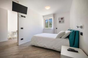 a white bedroom with a bed and a television at Appartamenti Gaggiolo 2 in Dro