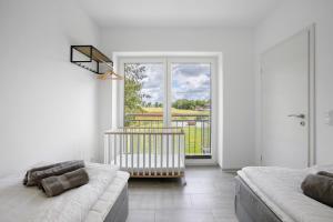 a white living room with a couch and a balcony at Ferienhaus Ebbe in Schülp