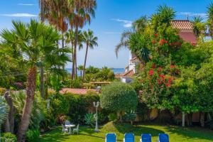 un jardín con sillas azules y palmeras en Exclusive Villa Elmessidor, en Marbella