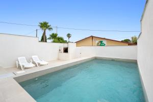 a swimming pool with two chairs and a house at Arenal in Camarles