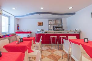 a restaurant with red tables and chairs and a kitchen at San Martino Apartment Riccardo in Cassibile