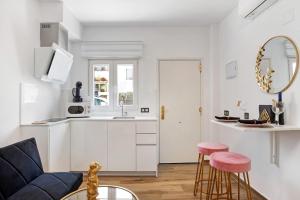 a kitchen and living room with white cabinets and pink stools at Esencia Vejer in Vejer de la Frontera