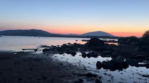 Rooms Foxford في فوكسفورد: غروب الشمس على مجموعة من المياه مع الجبال في الخلفية