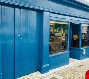 Rooms Foxford في فوكسفورد: واجهة متجر زرقاء اللون مع انعكاسات في النوافذ