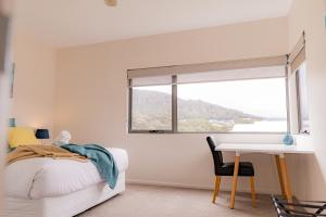 a bedroom with a bed and a desk and a window at Bicheno Sands-space and the sea in Bicheno