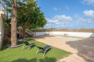 un patio con 2 sillas, un árbol y una piscina en Can Manya vacacional, en Alcanar