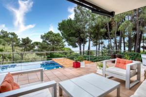 a patio with a table and chairs and a swimming pool at Design villa with sea views in San Pol de Mar