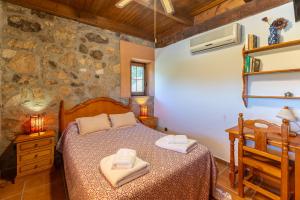 a bedroom with a bed and a stone wall at Finca La Lobera in Candeleda +29 photos