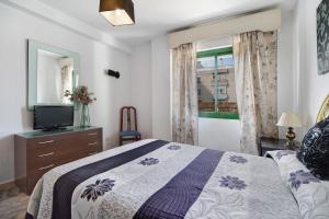 une chambre avec un lit, une télévision et une fenêtre dans l'établissement Apartamento en la mejor zona, à Jerez de la Frontera