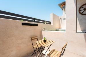 un patio con tavolo, sedie e orologio. di La Mihilla a Málaga