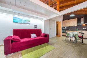 a living room with a red couch and a kitchen at Confortevole Loft Sud Sardegna in San Giovanni Suèrgiu