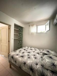 ein Schlafzimmer mit einem Bett in einem Zimmer mit einem Fenster in der Unterkunft Vos vacances à 800m de la plage de l anse figuier in Rivière-Pilote