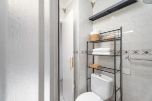 a bathroom with a toilet and towels on a shelf at Hand Made Suite Costa del Silencio in Costa Del Silencio +18 photos