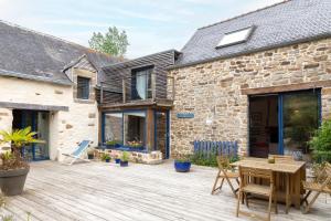 Un patio de una casa de piedra con una mesa de madera. en Gîte avec piscine-Cap Sizun, en Confort