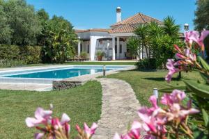 una casa con piscina y flores rosas en Luxury Villa Malva, en Benalup-Casas Viejas