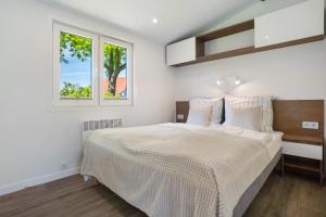 a white bedroom with a large bed and two windows at Haus Waldblick in Saal