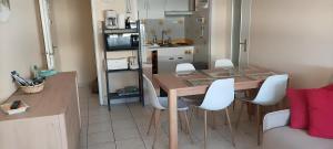 eine kleine Küche mit einem Tisch und weißen Stühlen in der Unterkunft Superbe Appartement - Vue Mer in Saint-Hilaire-de-Riez