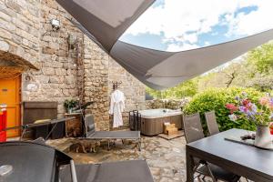 a patio with tables and chairs and a stone wall at Cocon avec jacuzzi in Labastide-de-Juvinas