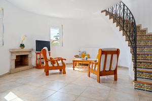 a living room with a staircase and chairs and a table at Villa Flor in Les tres Cales