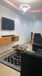 Una sala de estar con un televisor, un sofá y una mesa. en OA luxury apartment, 